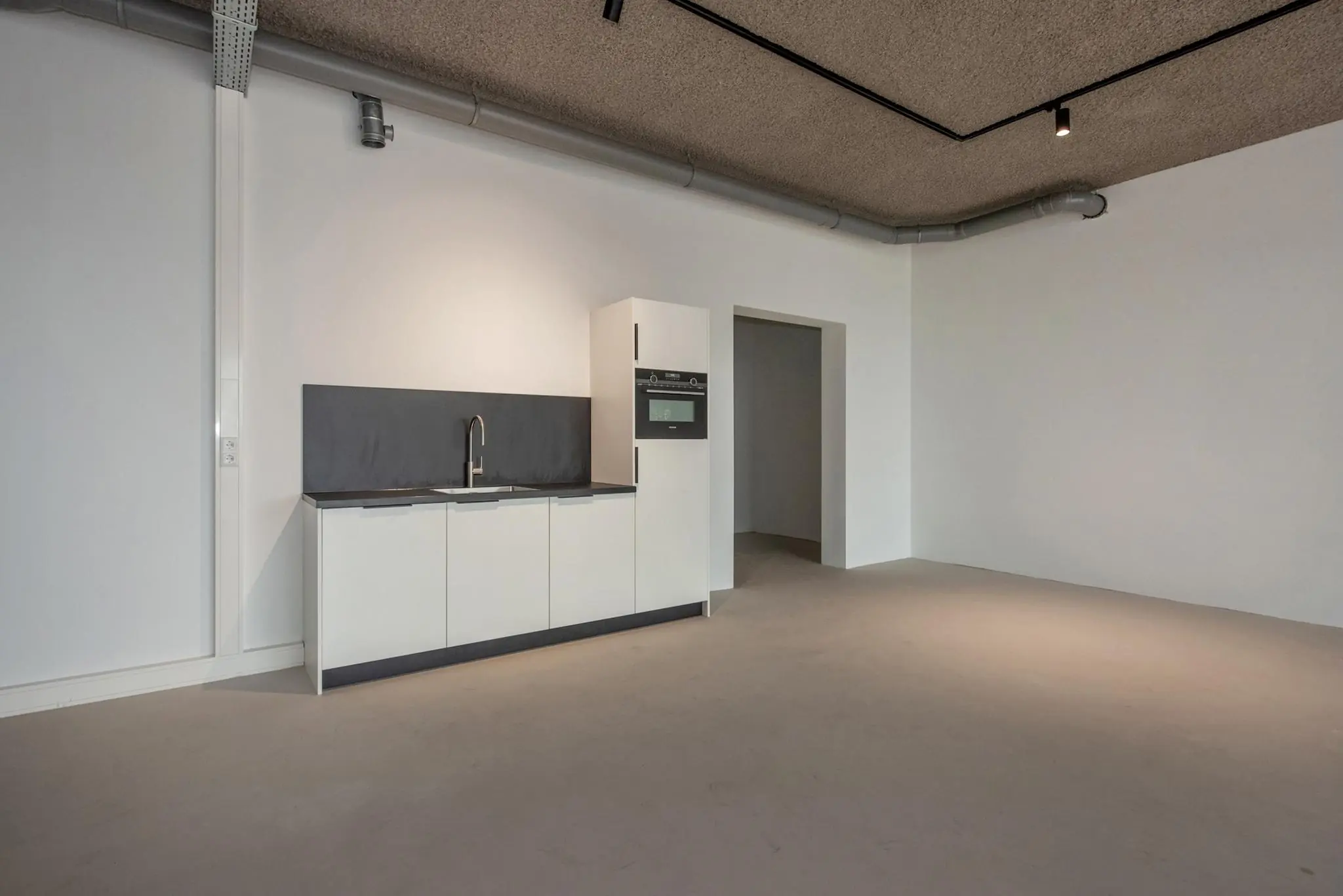 Moderne, minimalistische kitchenette in een lege ruimte aan de Saturnusstraat.