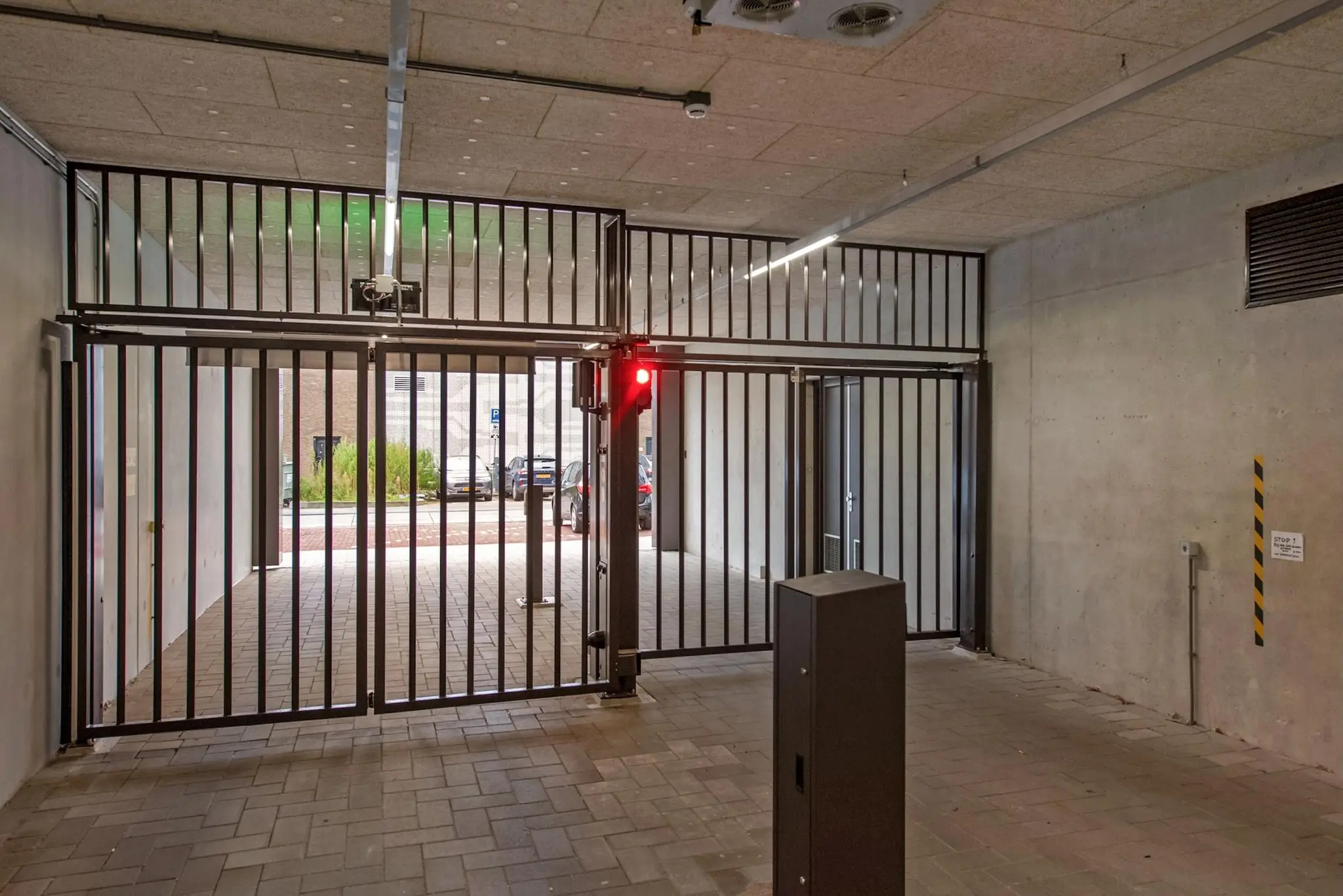 Beveiligde parkeergarage-ingang aan de Saturnusstraat met gesloten hek en rood stoplicht.