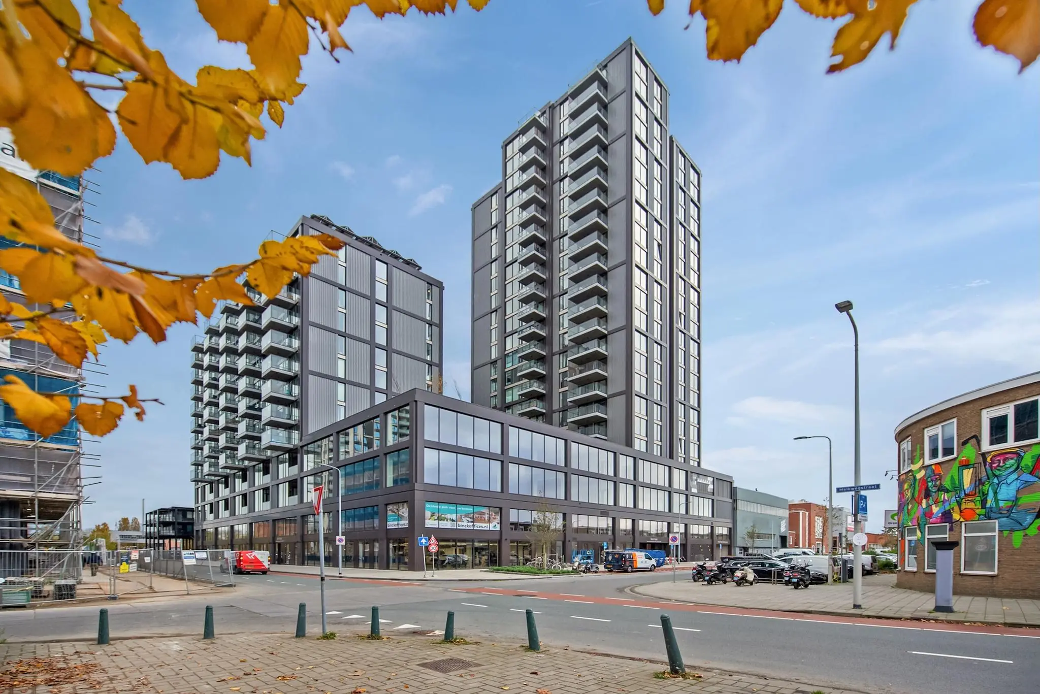 Moderne hoogbouw aan de Saturnusstraat met glazen gevels en herfstbladeren op de voorgrond.