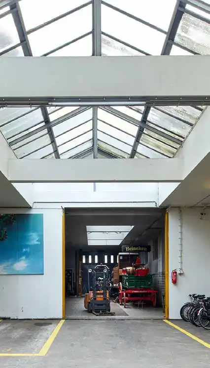 Magazijnruimte aan de Ruysdaelkade met industriële dakramen, een heftruck en Heineken-materialen.