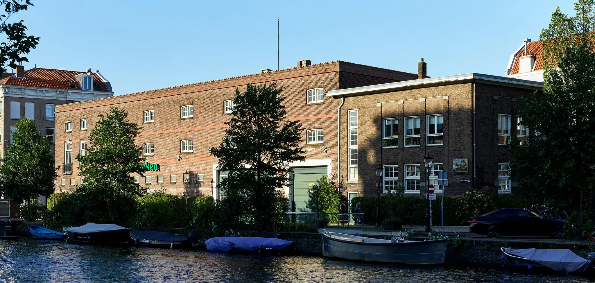 Bakstenen gebouwen aan de Ruysdaelkade in Amsterdam met aangemeerde boten langs het water.