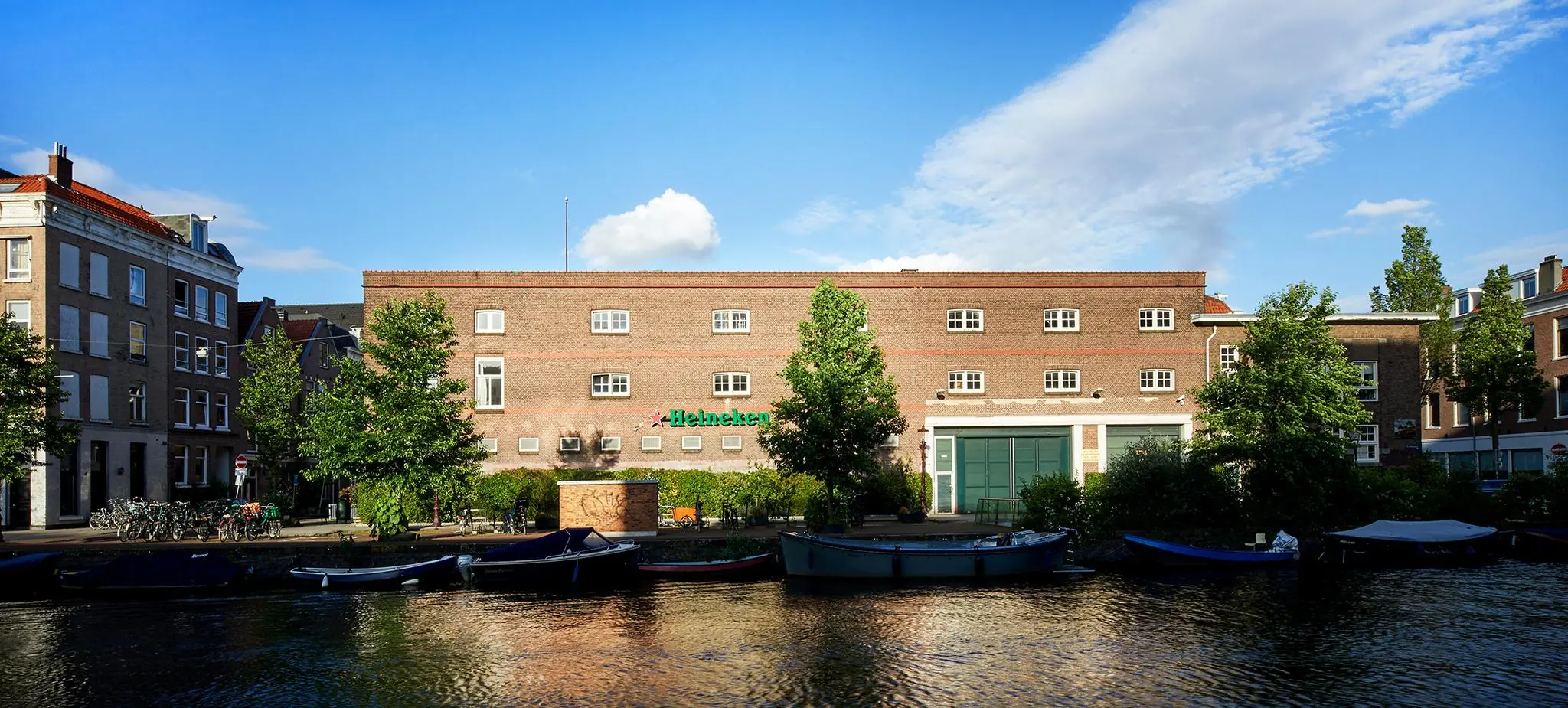 Vooraanzicht van het Heineken-pand aan de Ruysdaelkade in Amsterdam, met boten in de gracht op de voorgrond.