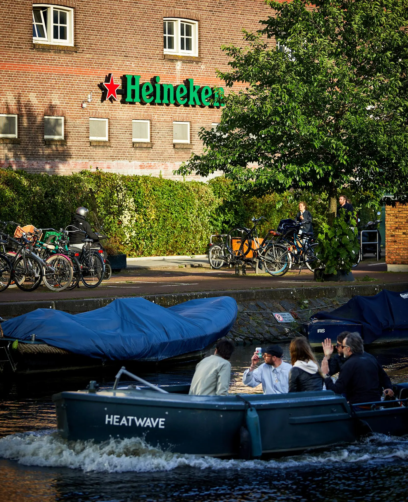 Een boot met mensen vaart over de Ruysdaelkade langs het Heineken-gebouw in Amsterdam.