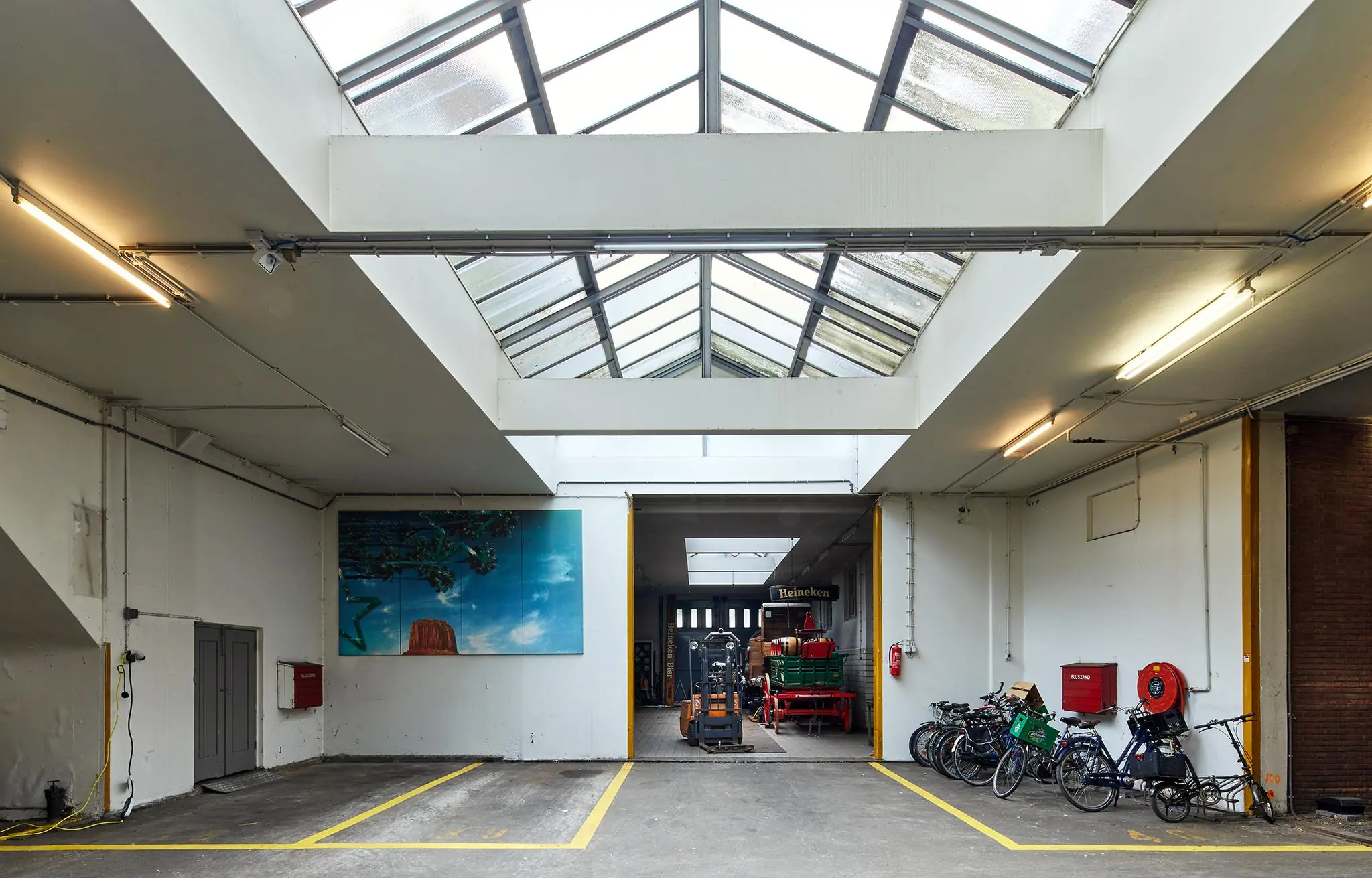 Overdekte garage aan de Ruysdaelkade met geparkeerde fietsen, kunst aan de muur en Heineken-objecten in de achterruimte.