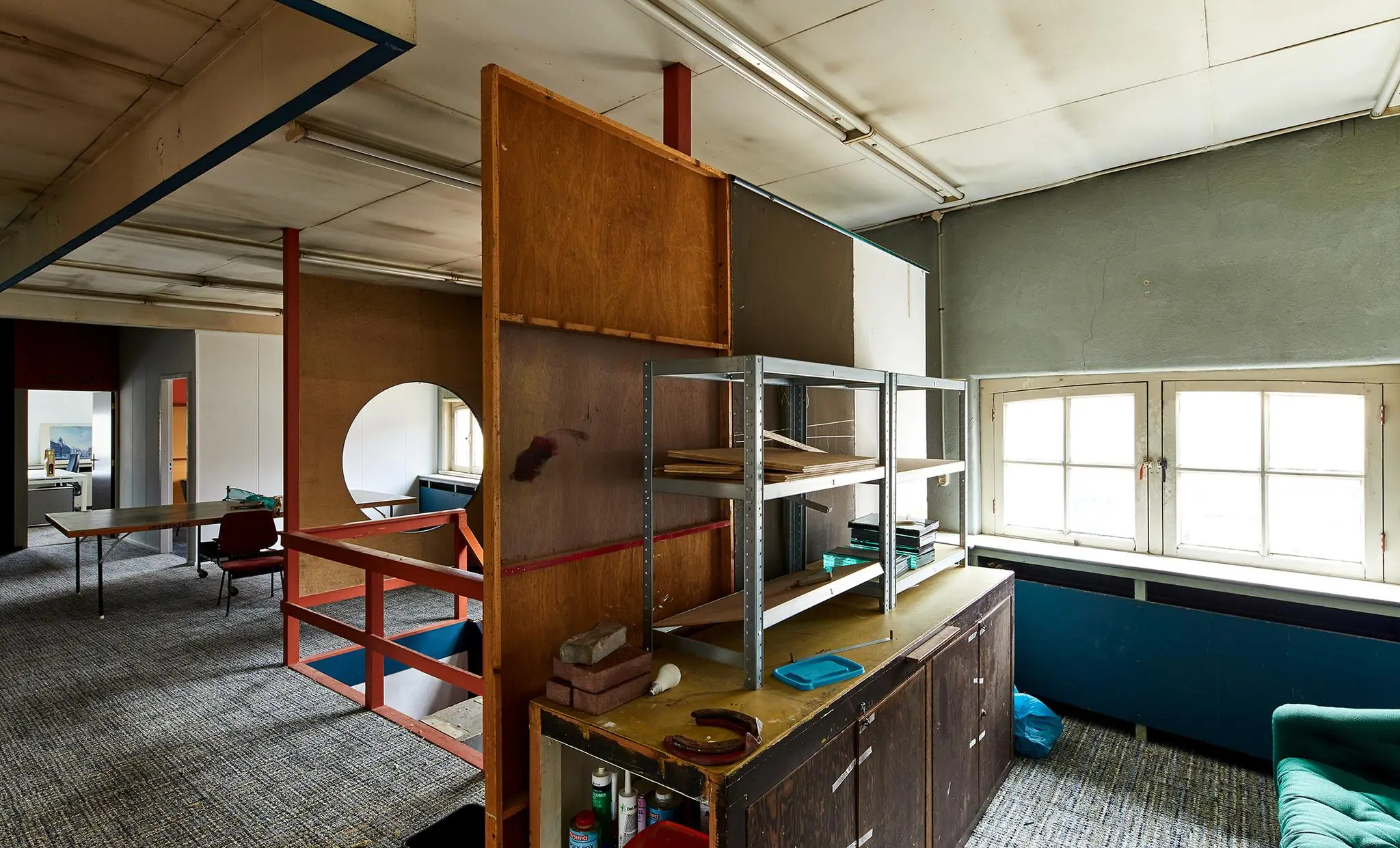 Verouderde en rommelige kantoorruimte aan de Ruysdaelkade met scheidingswanden, metalen stellingkast en bureaus.