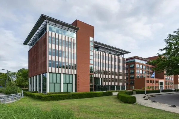 Modern kantoorgebouw aan de Lichtenauerlaan met roodbruine gevel en grote glaspartijen.