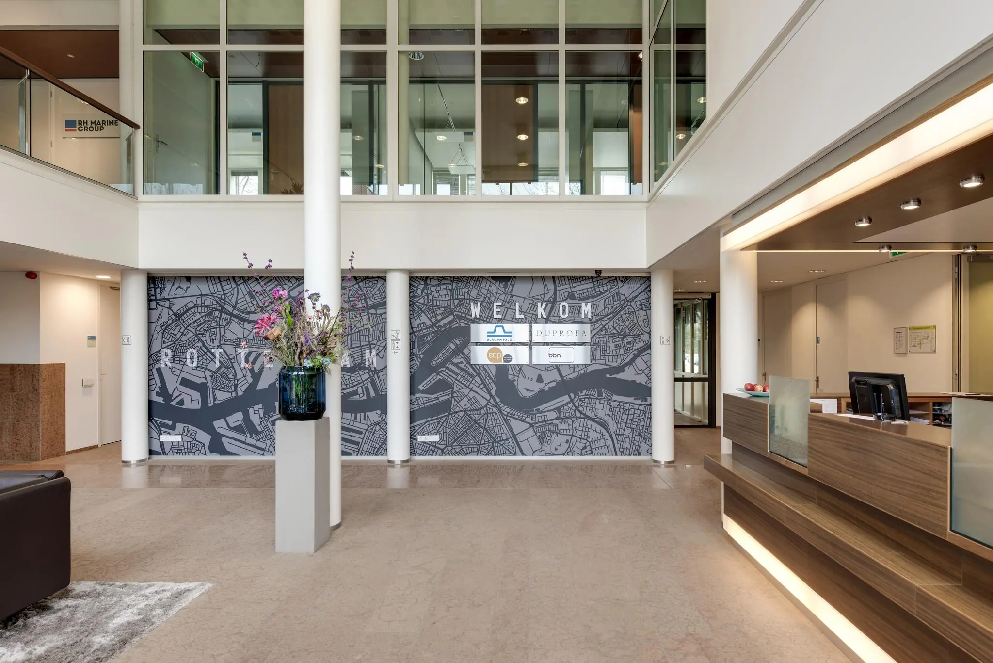 Moderne ontvangsthal aan de Lichtenauerlaan met balie, wandkaart van Rotterdam en bedrijfslogo’s.