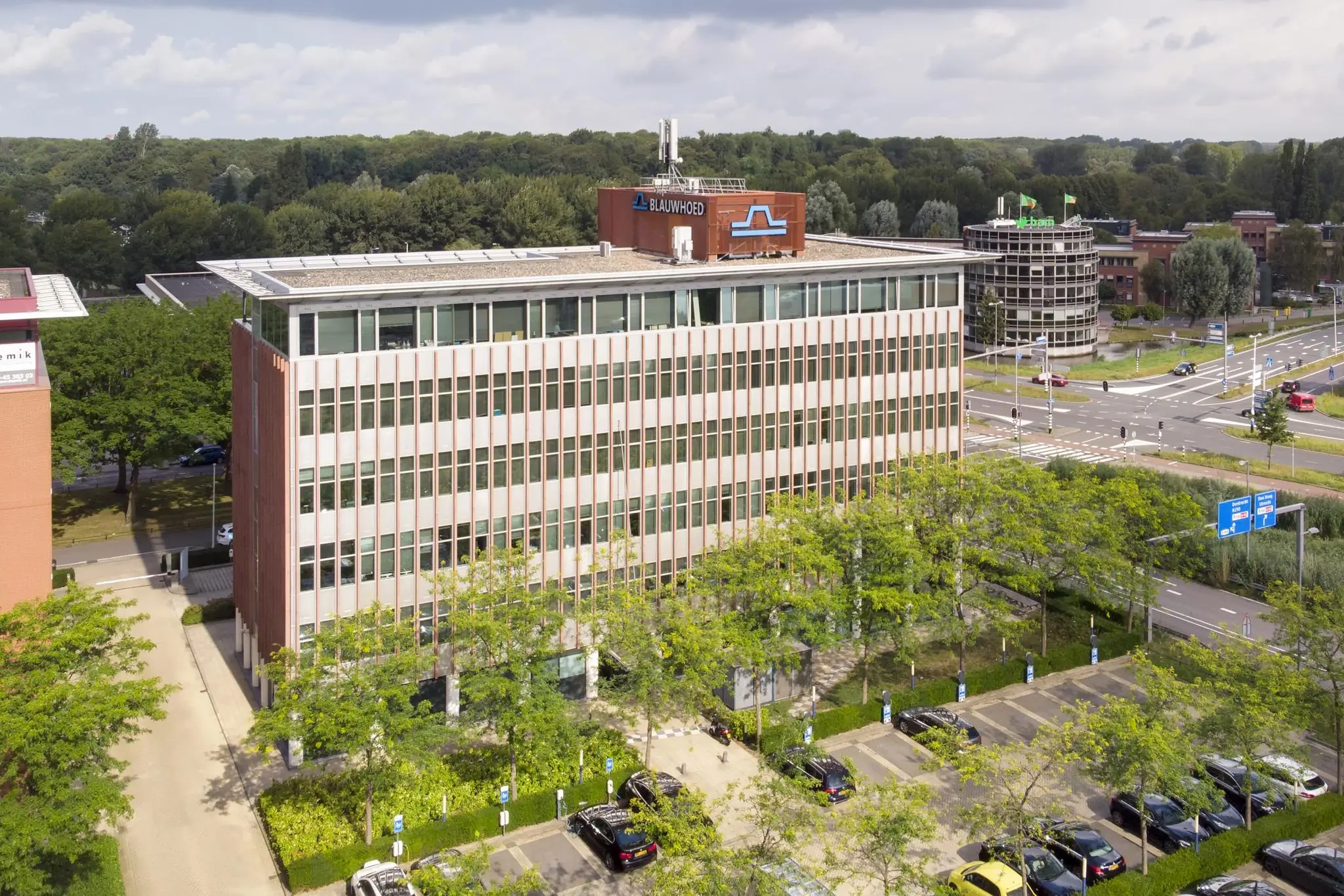 Kantoorgebouw van Blauwhoed aan de Lichtenauerlaan in Rotterdam, omringd door bomen en parkeerplaatsen.
