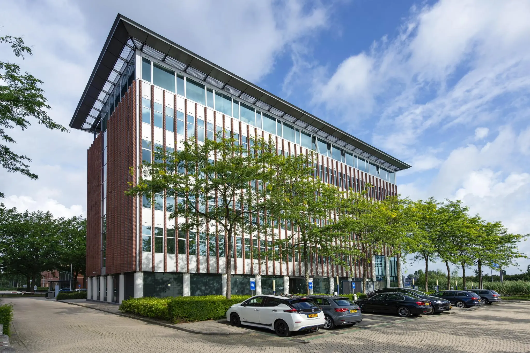 Modern kantoorgebouw aan de Lichtenauerlaan met geparkeerde auto's op een zonnige dag.