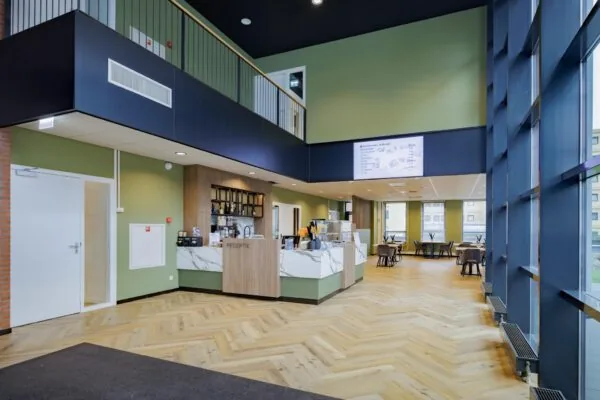 Moderne ontvangsthal met receptiebalie, zithoek en grote ramen in een gebouw aan de Hiridostraat.
