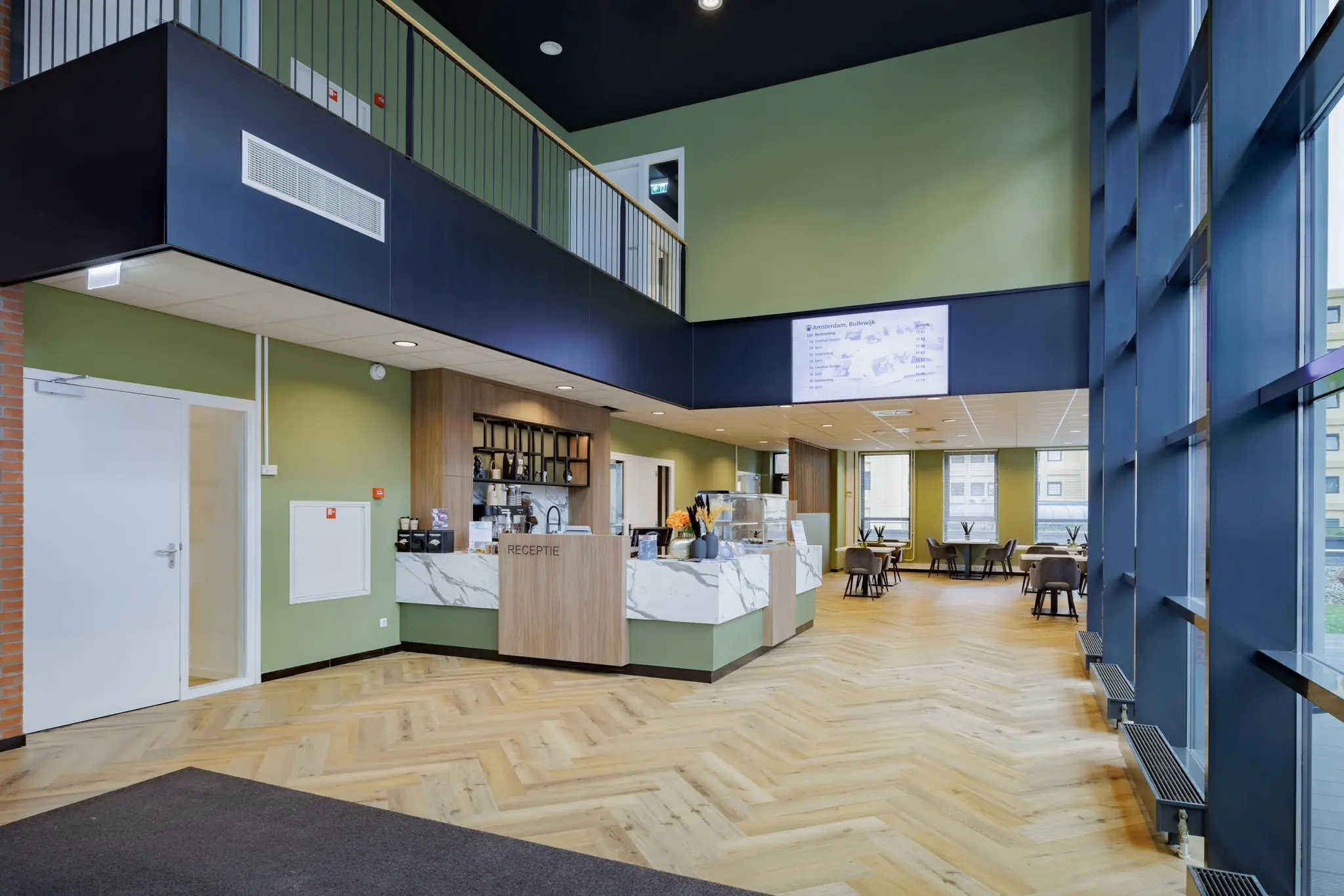 Moderne ontvangsthal met receptiebalie, zithoek en grote ramen in een gebouw aan de Hiridostraat.