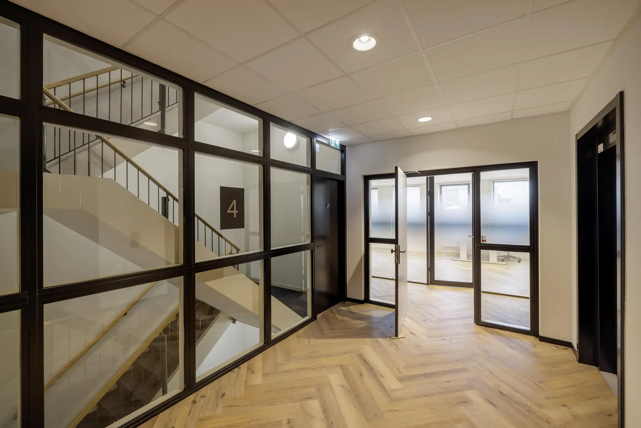 Moderne kantoorhal op de vierde verdieping aan de Hiridostraat met zicht op een trappenhuis en glazen wanden.