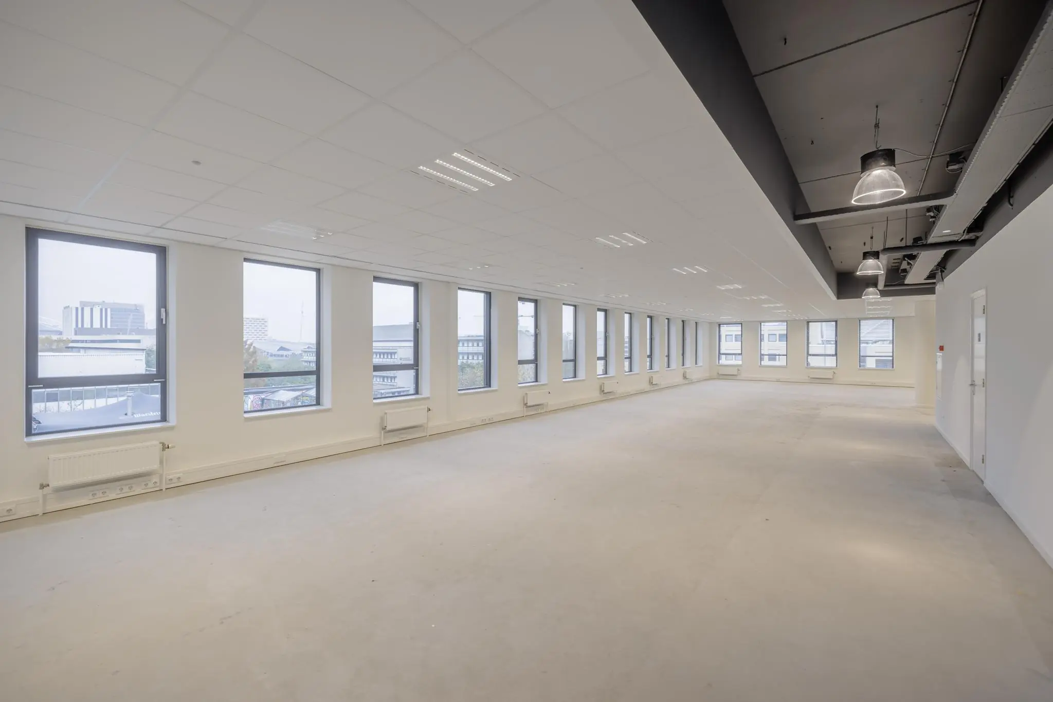 Leeg kantoorpand aan de Hiridostraat met grote ramen en systeemplafond.