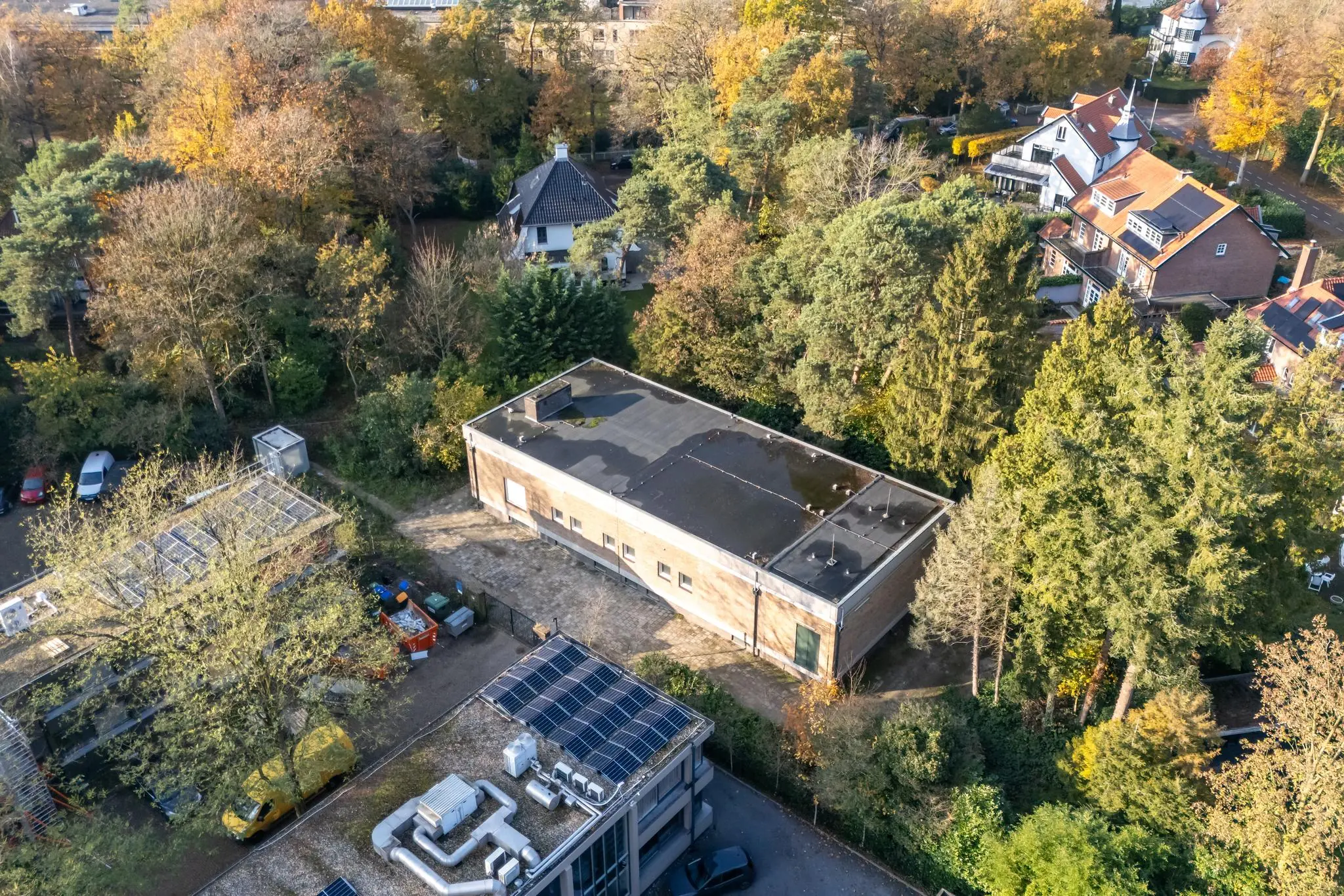 Luchtfoto van een gebouw aan de Rembrandtlaan, omringd door bomen en nabijgelegen woonhuizen.