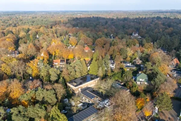 Luchtfoto van de Rembrandtlaan omringd door herfstkleurige bomen en villa’s in een bosrijke villawijk.