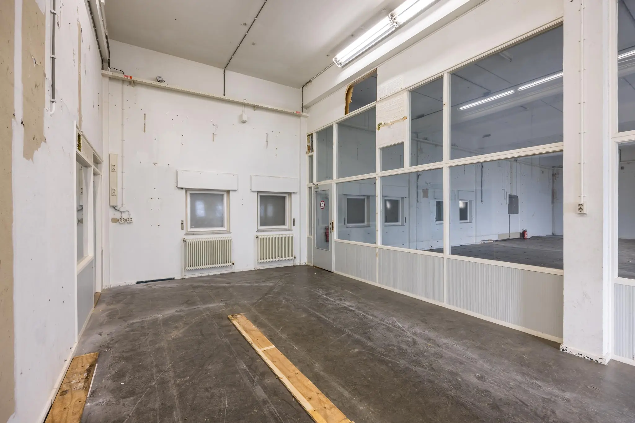 Leegstaande industriële ruimte aan de Rembrandtlaan met witte muren, grote ramen en een betonnen vloer.