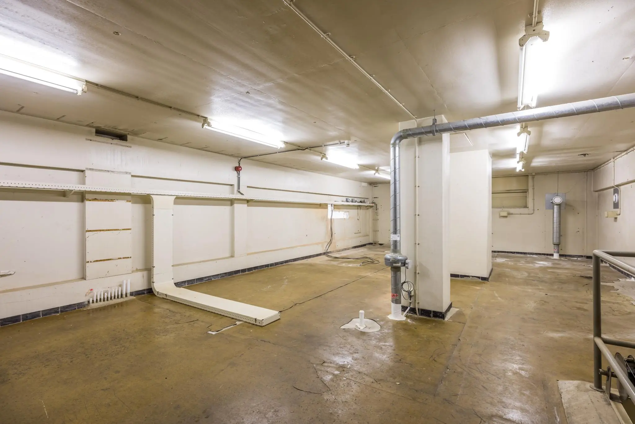 Lege, industrieel ogende kelderruimte met buizen, leidingen en tl-verlichting aan het plafond in een pand aan de Rembrandtlaan.