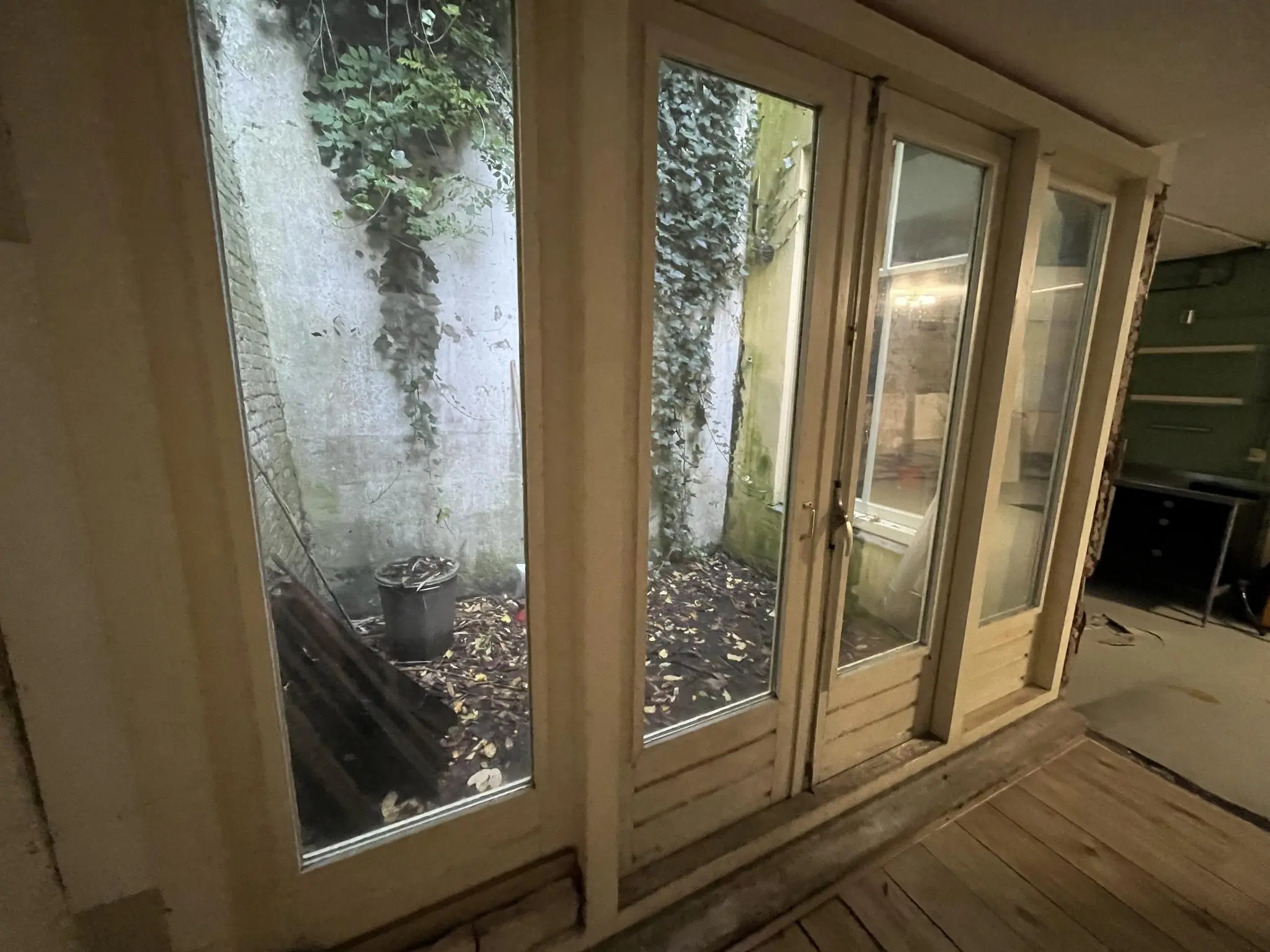 Grote glazen deuren met uitzicht op een kleine, met bladeren bedekte patio aan de Nobeldwarsstraat.