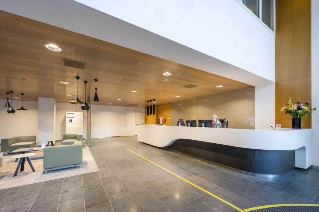 Moderne receptieruimte in kantoorgebouw Hoekenrode met strakke balie, zitgedeelte en warme houten accenten.