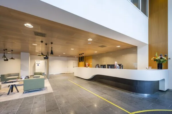 Moderne receptieruimte in kantoorgebouw Hoekenrode met strakke balie, zitgedeelte en warme houten accenten.