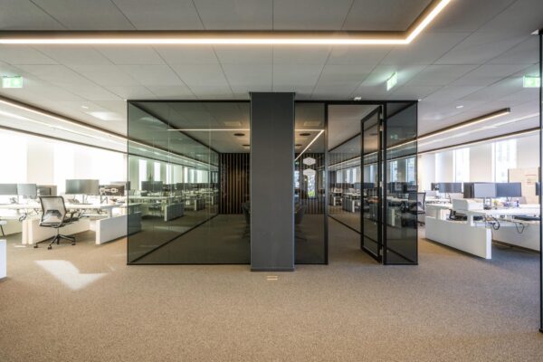 Modern kantoorinterieur in gebouw Hoekenrode met glazen vergaderruimtes en open werkplekken.