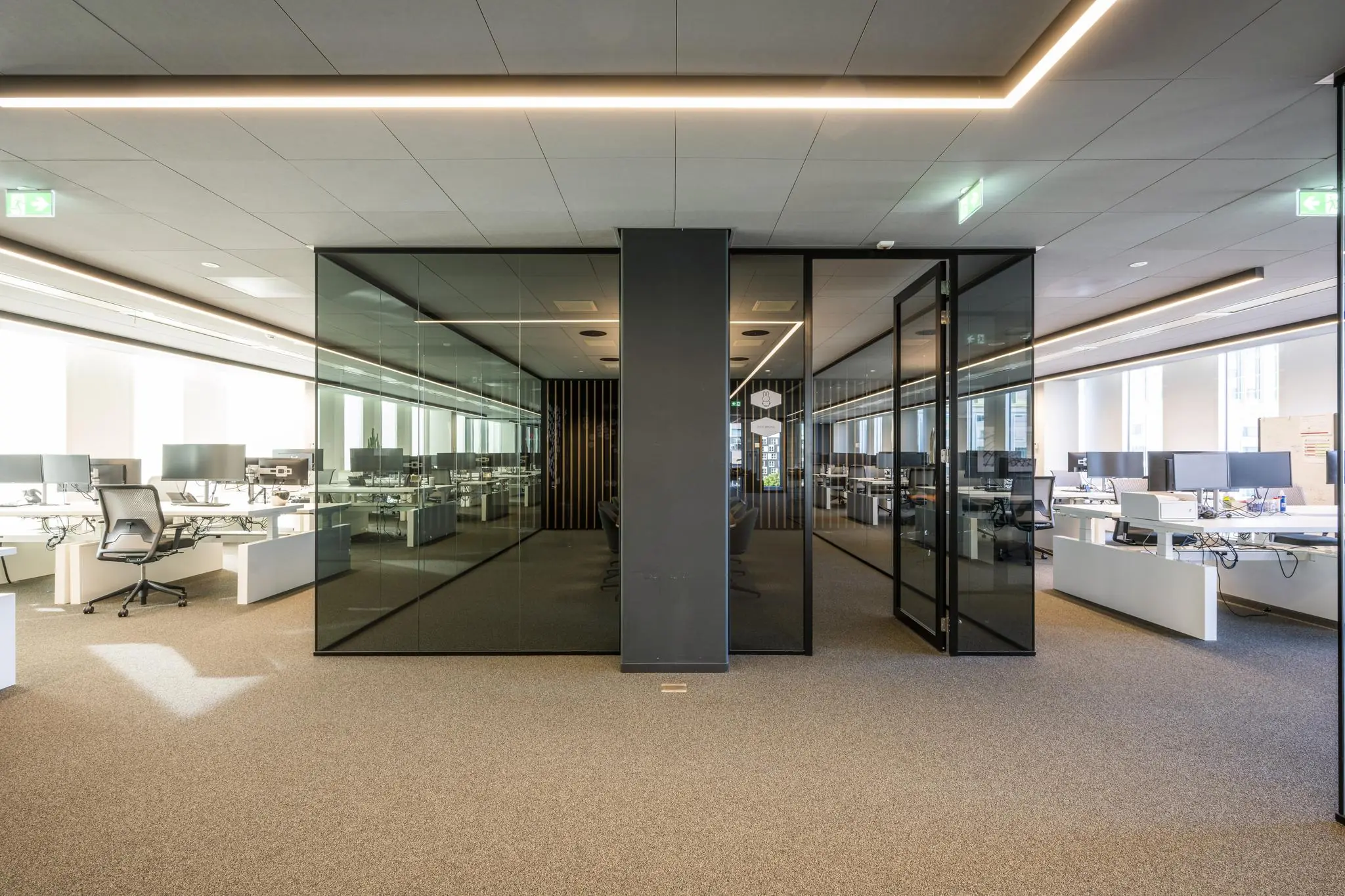Modern kantoorinterieur in gebouw Hoekenrode met glazen vergaderruimtes en open werkplekken.