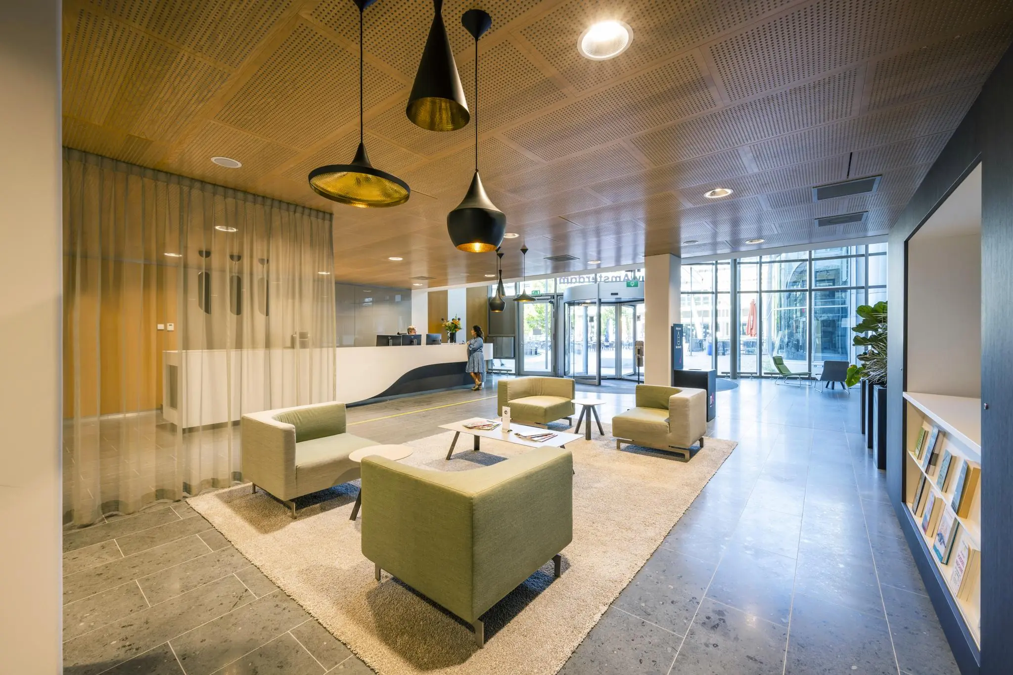 Moderne en ruime entreehal van gebouw Hoekenrode met zithoek, receptiebalie en veel natuurlijk licht.