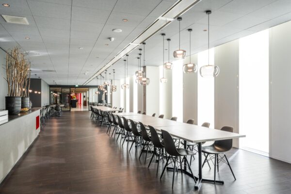Moderne en lichte vergaderruimte in Hoekenrode met lange tafels, zwarte stoelen en hanglampen.