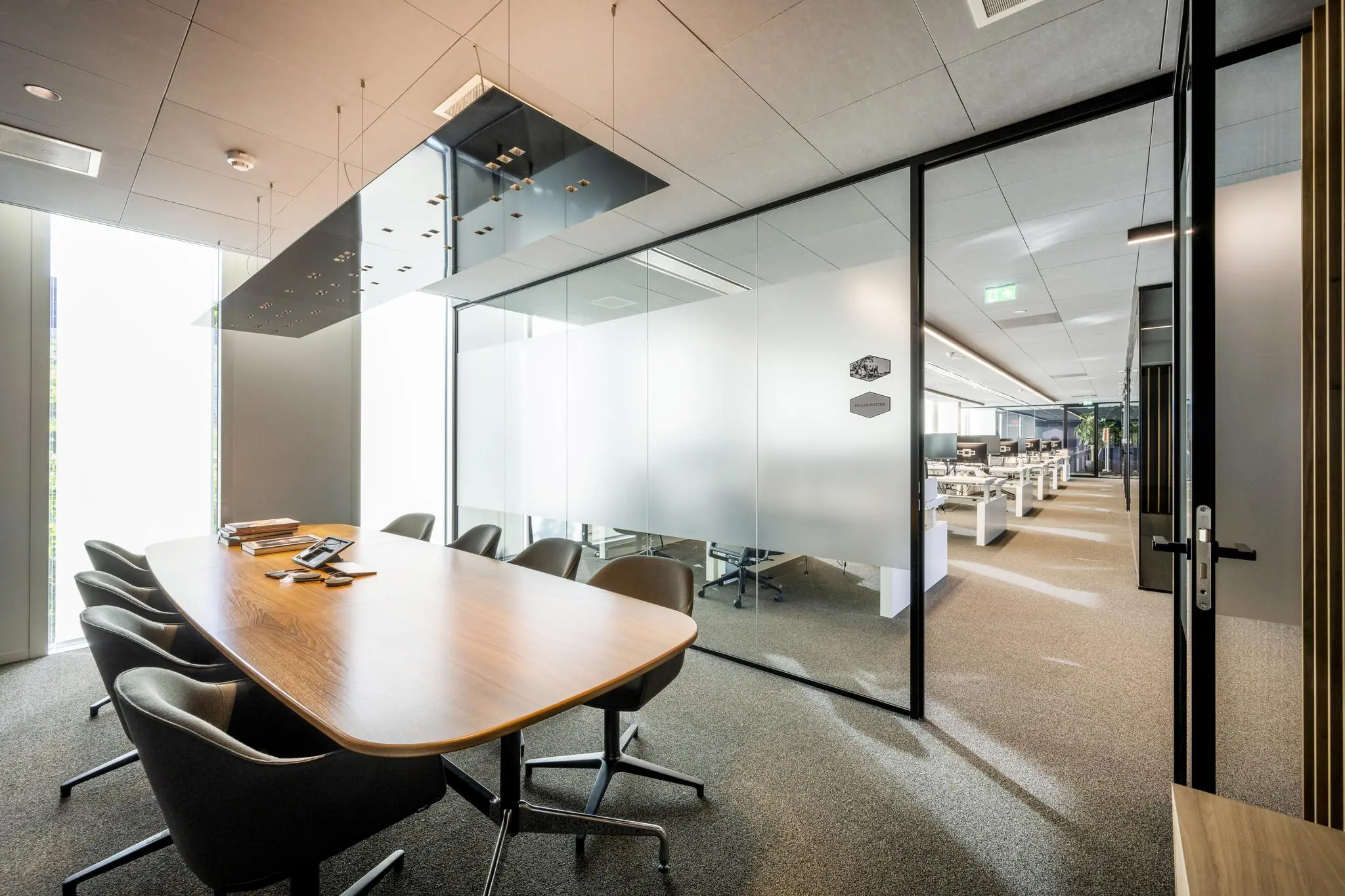 Moderne vergaderruimte in kantoorpand Hoekenrode met glazen wanden en uitzicht op open kantoorruimte.