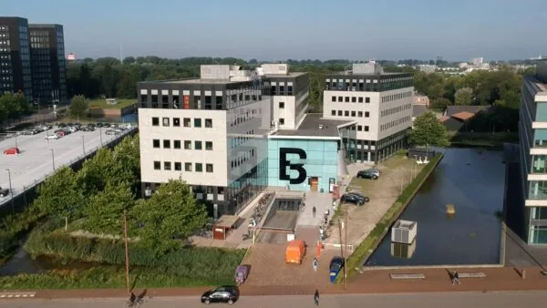 Luchtfoto van het gebouw op het John M. Keynesplein met de prominente letter “B” op de glazen entree.