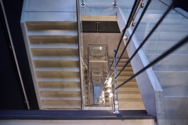 Doorkijk vanaf boven in een modern trappenhuis op het John M. Keynesplein met betonnen treden en metalen leuningen.