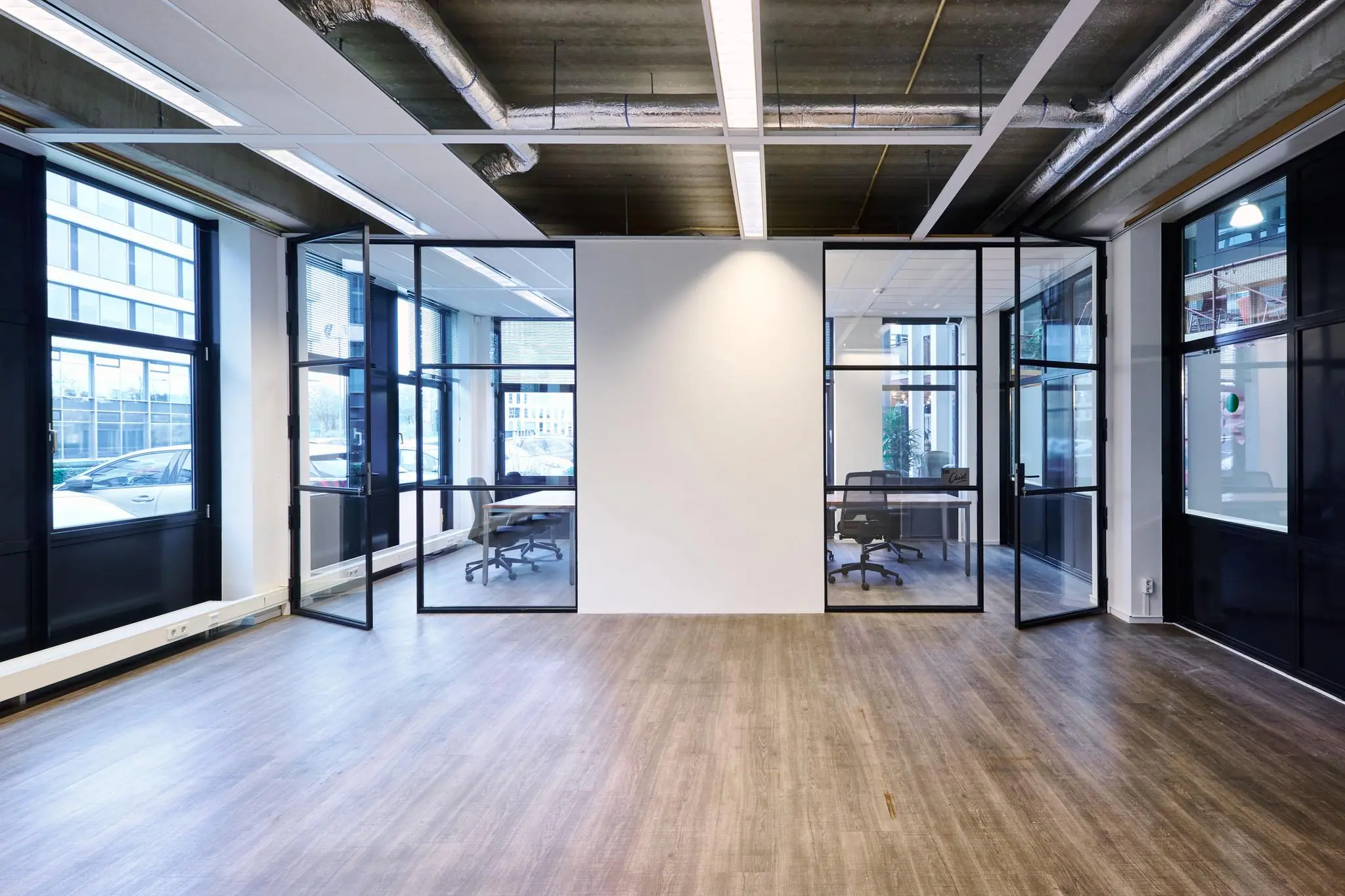 Moderne kantoorruimte aan het John M. Keynesplein met glazen vergaderruimtes en een houten vloer.