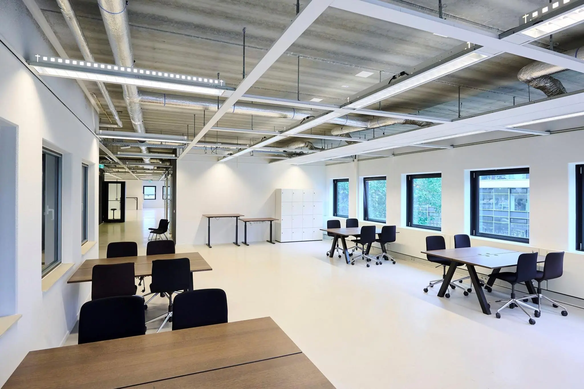 Moderne, lichte kantoorruimte aan het John M. Keynesplein met meerdere werkplekken, ramen en industriële plafonduitwerking.
