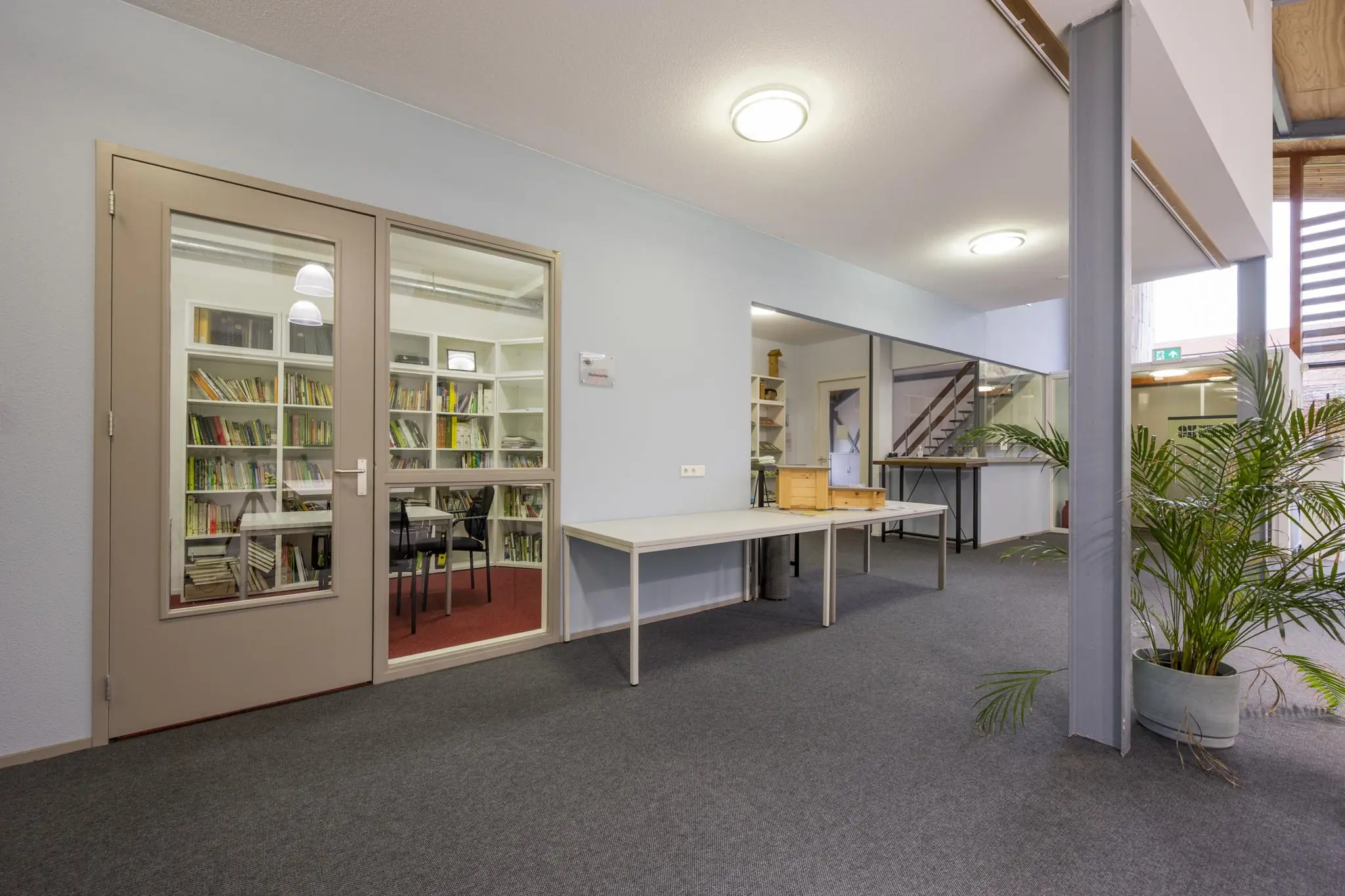 Moderne, lichte kantoorruimte aan de Vogelvlinderweg met glazen vergaderruimte en boekenwand.