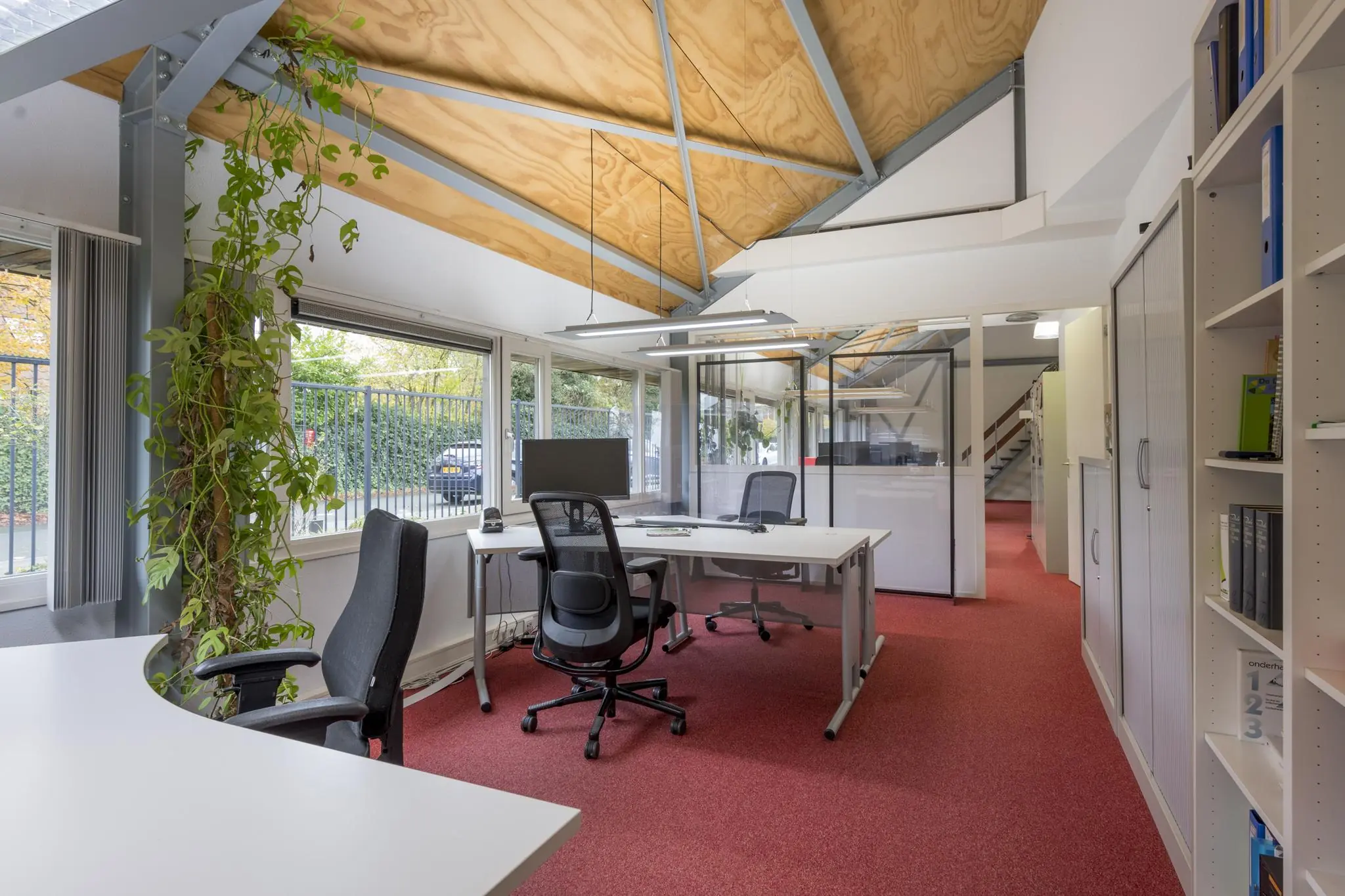 Modern kantoorinterieur aan de Vogelvlinderweg met bureaus, kantoormeubilair en grote ramen met uitzicht op buiten.