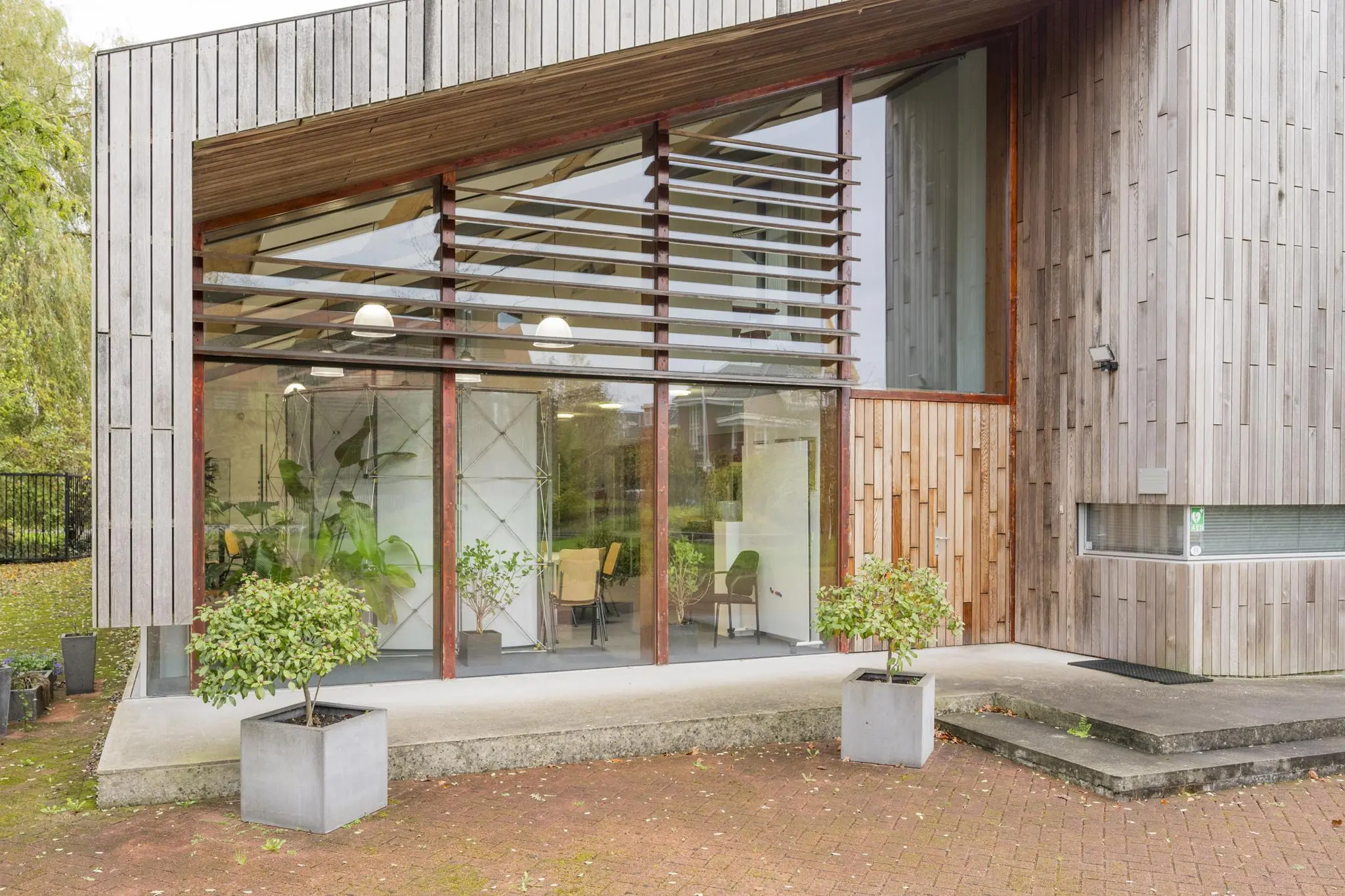Modern houten kantoorgebouw aan de Vogelvlinderweg met grote ramen en planten voor de gevel.