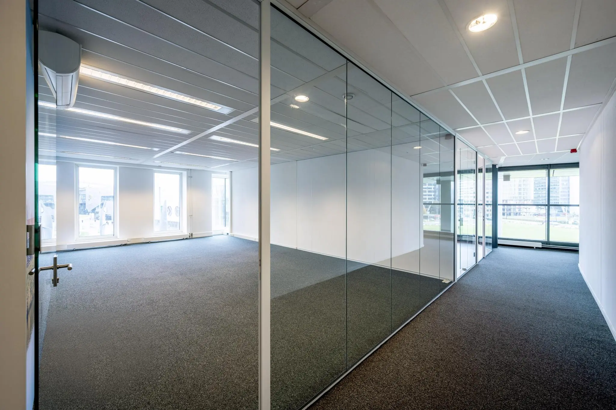 Leeg modern kantoor met glazen wanden aan de Johan Cruijff Boulevard en uitzicht op omliggende gebouwen.