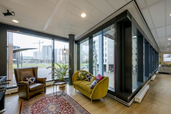 Modern ingerichte loungehoek met uitzicht op de Johan Cruijff Boulevard en omliggende kantoorgebouwen.