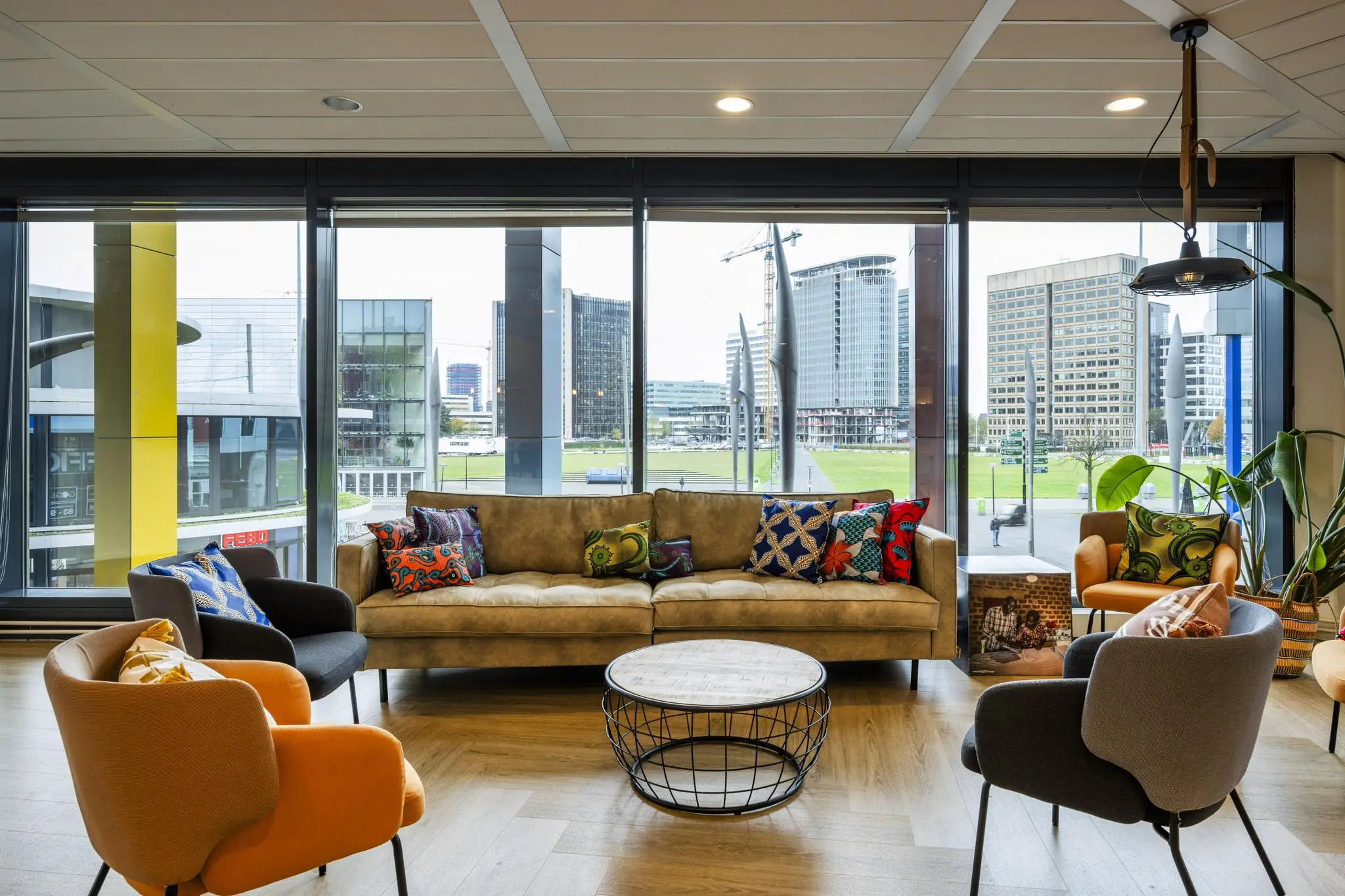 Moderne loungehoek met kleurrijke stoelen en kussens, uitzicht op de Johan Cruijff Boulevard in Amsterdam.