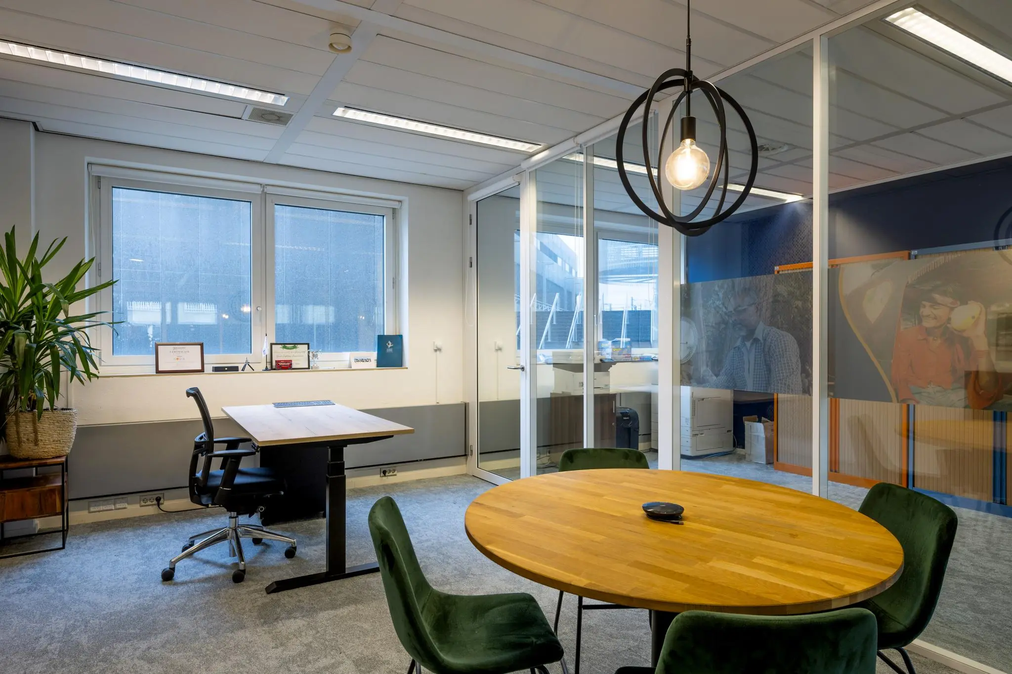 Modern kantoor aan de Johan Cruijff Boulevard met vergadertafel, bureau en glazen wanden met fotoprints.