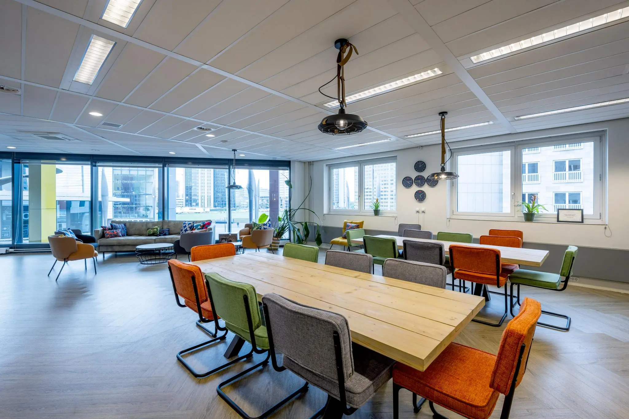 Moderne en kleurrijke vergaderruimte aan de Johan Cruijff Boulevard met grote ramen en uitzicht op kantoorgebouwen.