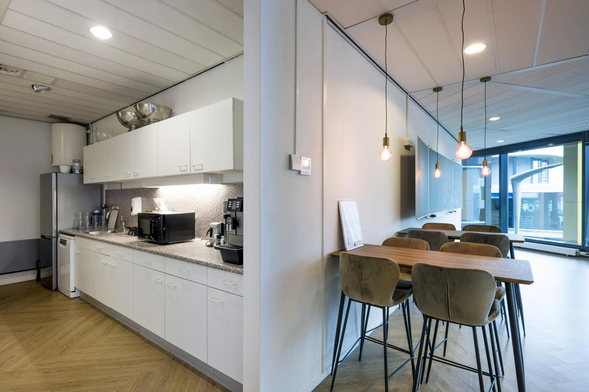 Moderne kantoorpantry met een keukenblok en aangrenzende zithoek aan de Johan Cruijff Boulevard.