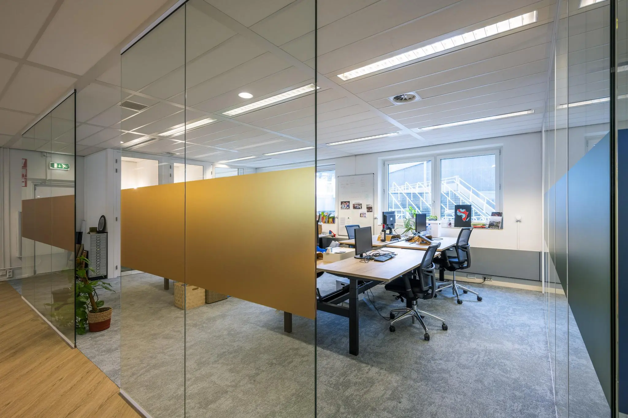 Modern kantoorinterieur aan de Johan Cruijff Boulevard met glazen wanden, bureaus en computers.