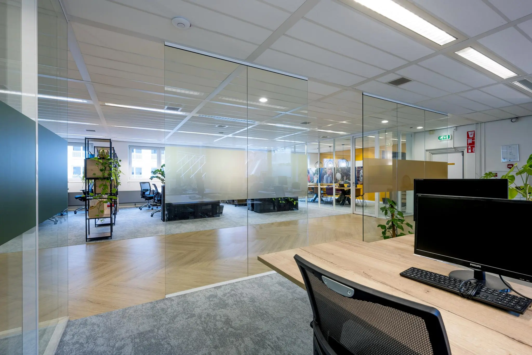Modern kantoorinterieur aan de Johan Cruijff Boulevard met glazen wanden, bureaus en groene accenten.