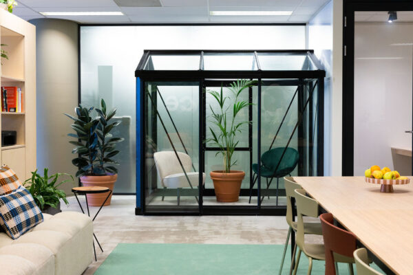 Moderne kantoorruimte aan de Johan Huizingalaan met glazen vergaderkas, planten, zitgedeelte en vergadertafel.