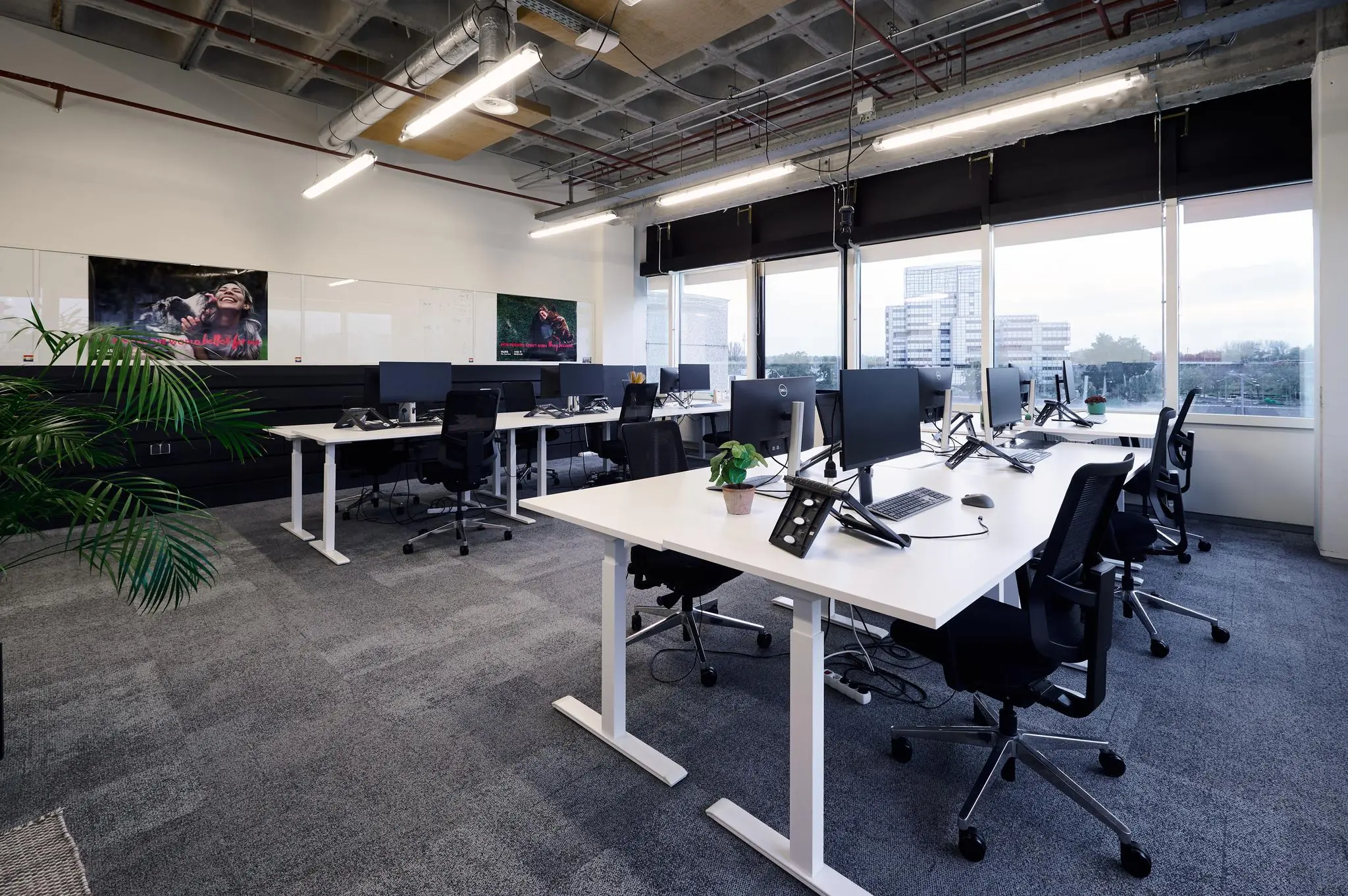 Modern kantoorinterieur aan de Johan Huizingalaan met bureaus, computers en uitzicht op kantoorgebouwen.