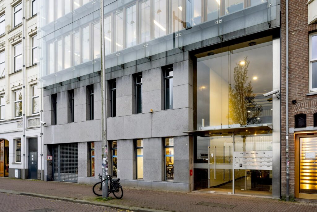 Modern kantoorgebouw met glazen entree aan de De Ruijterkade 112 in Amsterdam.