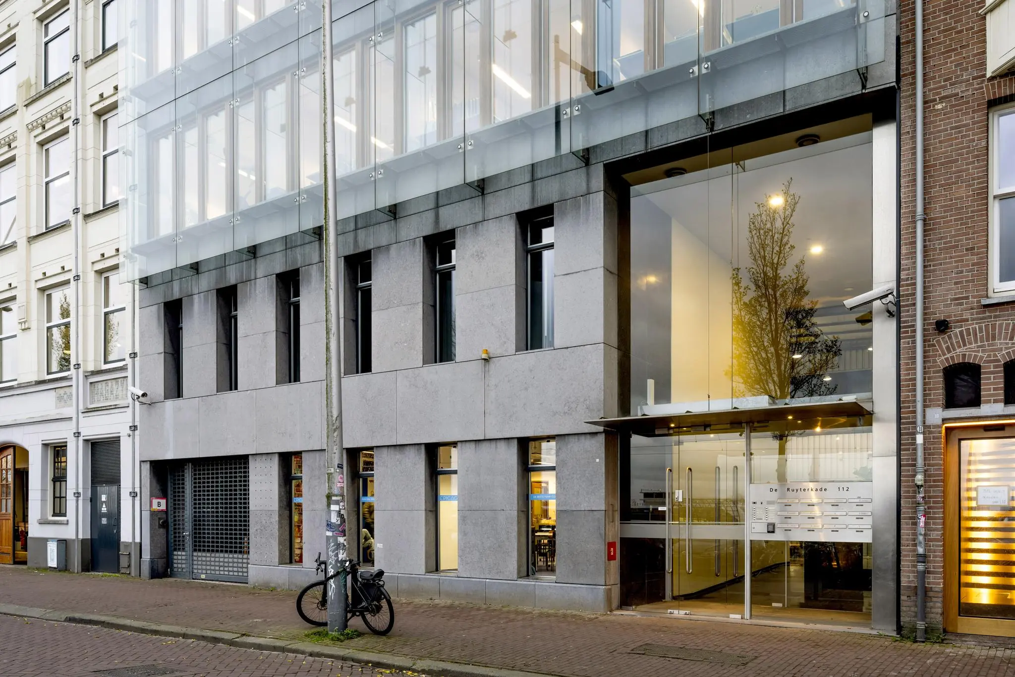 Modern kantoorgebouw met glazen entree aan de De Ruijterkade 112 in Amsterdam.
