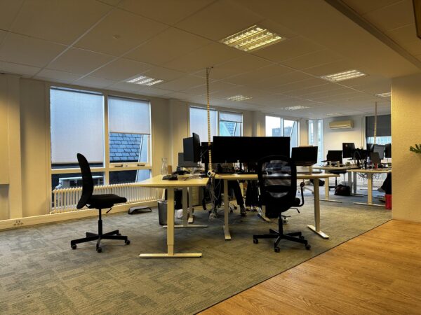 Moderne kantooruimte aan de Koninginnegracht met meerdere werkplekken, bureaustoelen en computeropstellingen.