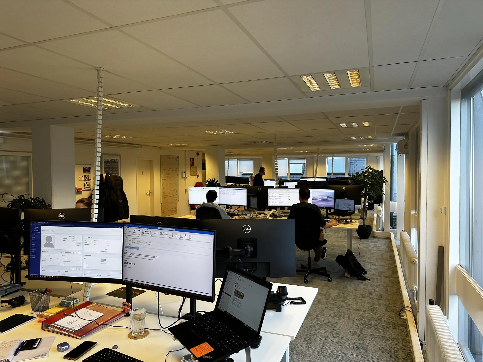 Open kantoorruimte aan de Koninginnegracht met meerdere medewerkers werkend achter computerschermen.